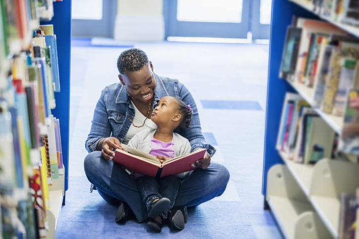 Mother reading to little girl at the library