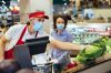 Supermarket employee helping a customer choose vegetable during coronavirus pandemic