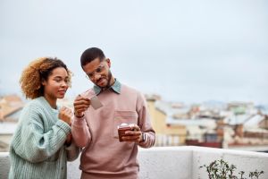 Couple Looking At Instant Print Selfie On Rooftop