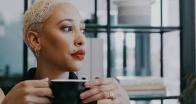Shot of a young businesswoman drinking coffee in an office