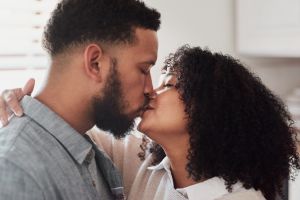 Shot of a young couple kissing in their kitchen at home