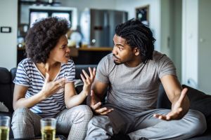 Angry African American couple arguing in the living room.