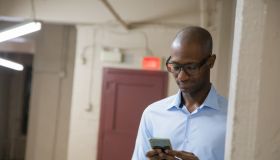 Middle-Aged bald African descent black male businessman hides to use social media