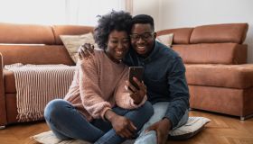 African American couple looking at smart phone at home
