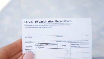 Woman holding covid-19 vaccination record card outdoors