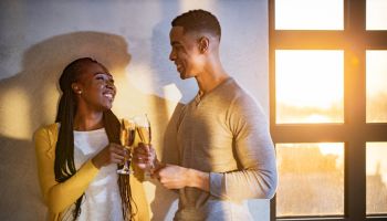 Happy black couple toasting at home.