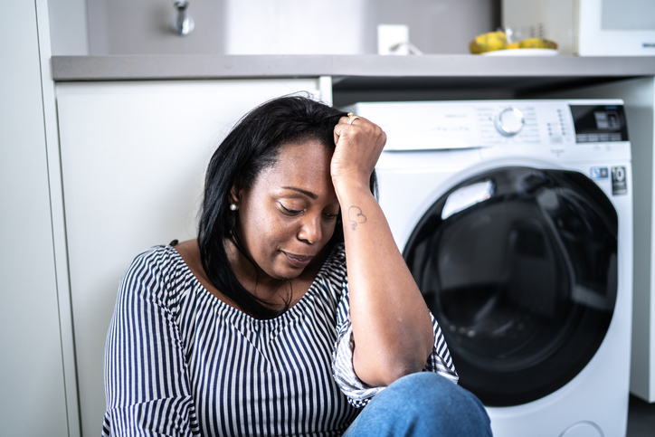 Depressed mature woman sitting on the ground at home