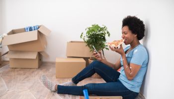 African American woman taking pizza break while renovating her apartment