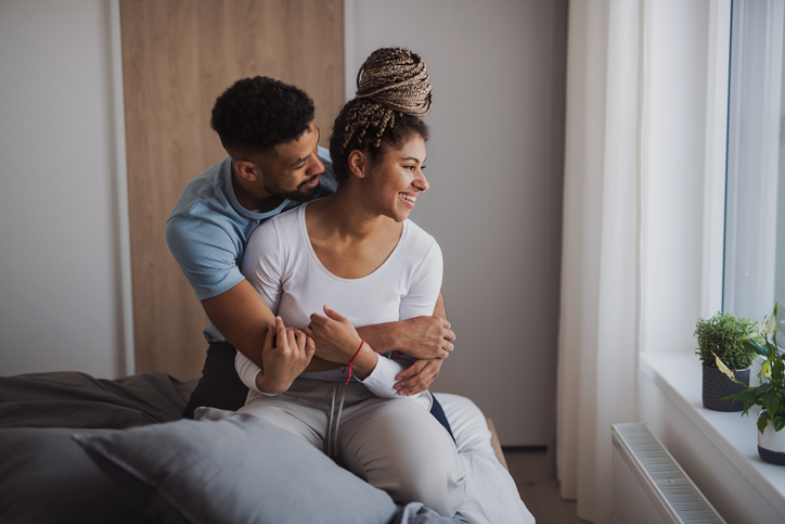 Portrait of young couplehugging indoors at home, laughing.