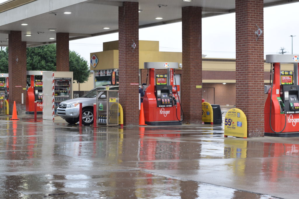 A customer pumps gas into his car at a Kroger gas station on a rainy day