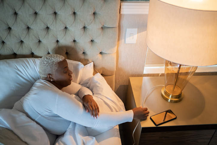 Woman waking and and turning on bed lamp at home