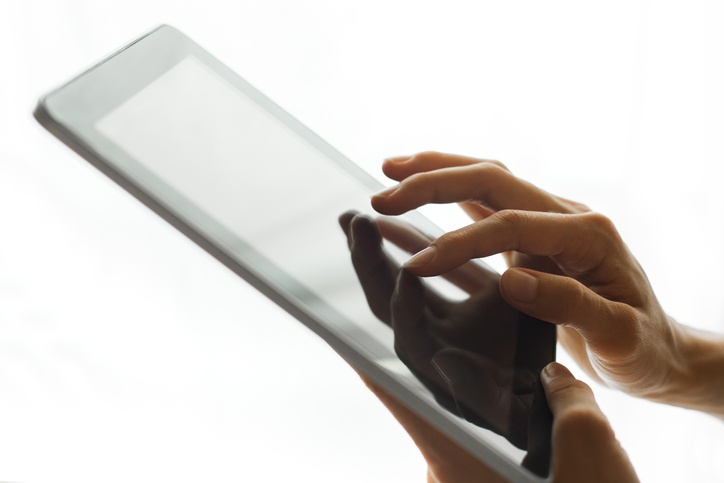 Person's hands holding tablet with touch screen. Empty white copy space background.
