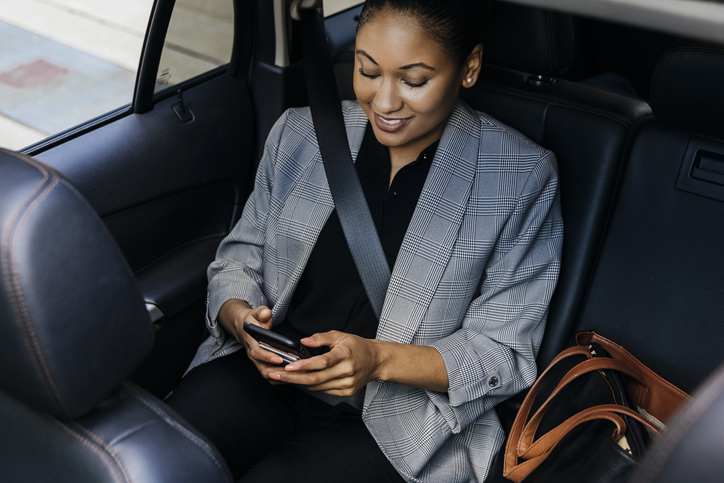 High angle view of businesswoman using smart phone sitting in backseat of car