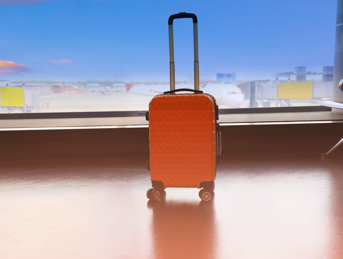 Orange travel suitcases in the airport terminal waiting area, summer vacation concept, traveling and enjoying concept