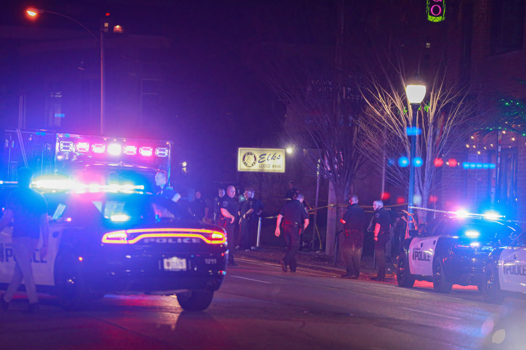 Members of law enforcement work at the scene of a shooting...