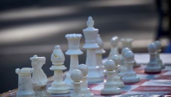 Closeup of white chess pieces lined up ready for play in Union Square Park, 14th Street, Manhattan, New York City