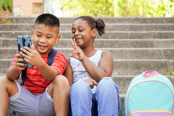 Happy multiethnic children using mobile phone for vlogging
