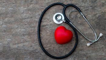 Stethoscope and red heart on old wooden background