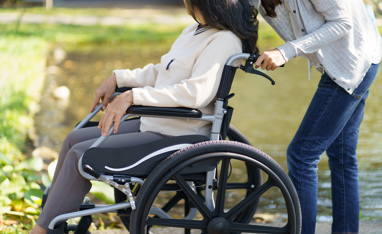 Nursing home. Young caregiver helping senior woman in wheelchair.