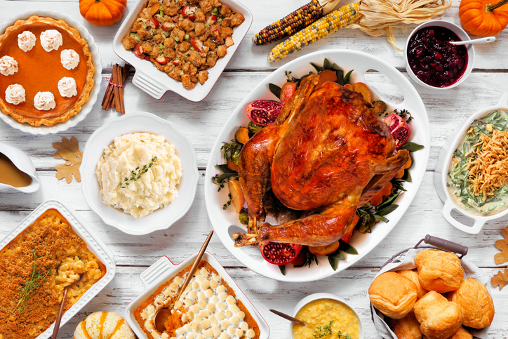 Delicious Thanksgiving turkey dinner. Above view table scene on a rustic white wood background. Turkey, mashed potatoes, stuffing, pumpkin pie and sides.