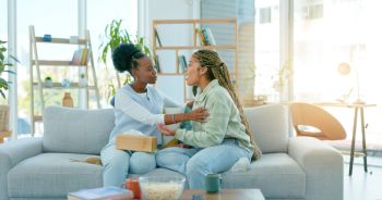 Sad women, friends and support on sofa in home, care and conversation for anxiety. African girls, depression and comfort on couch for kindness, empathy and help to console in communication together