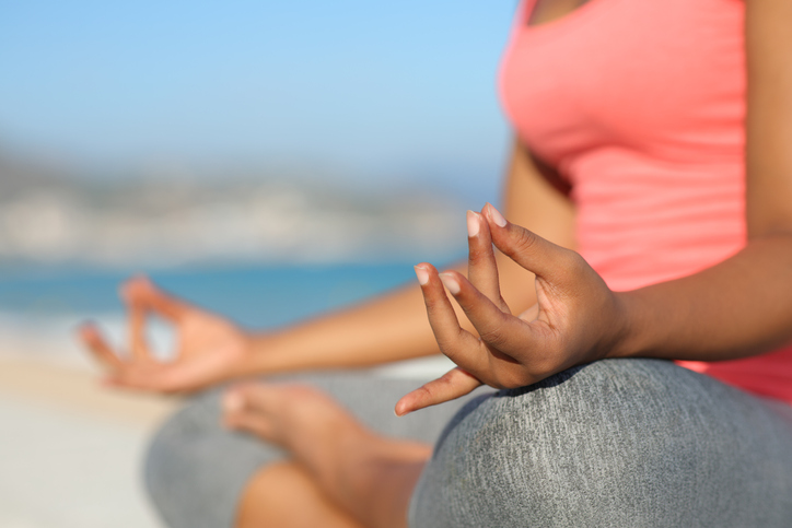 Black yogi hands doing yoga in the beach