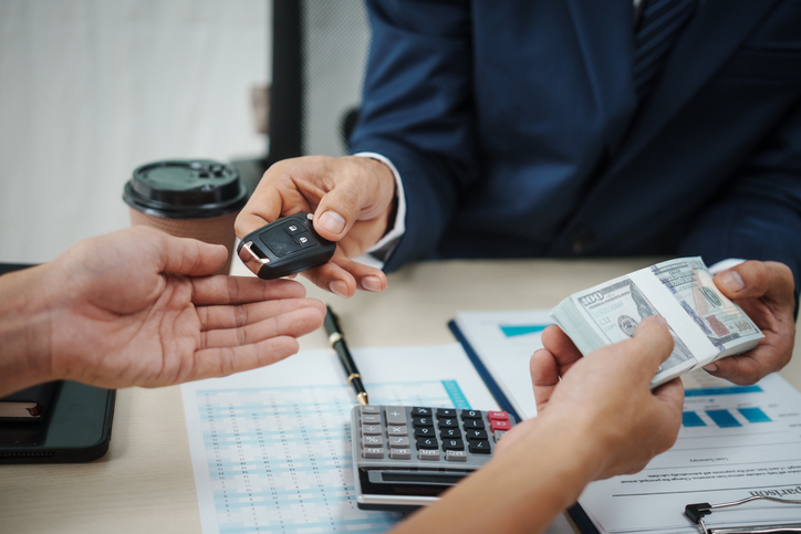 A businessman holds the key to success in car finance, focusing on sales, insurance, and investment. He manages contracts and agreements in a dynamic auto dealership environment