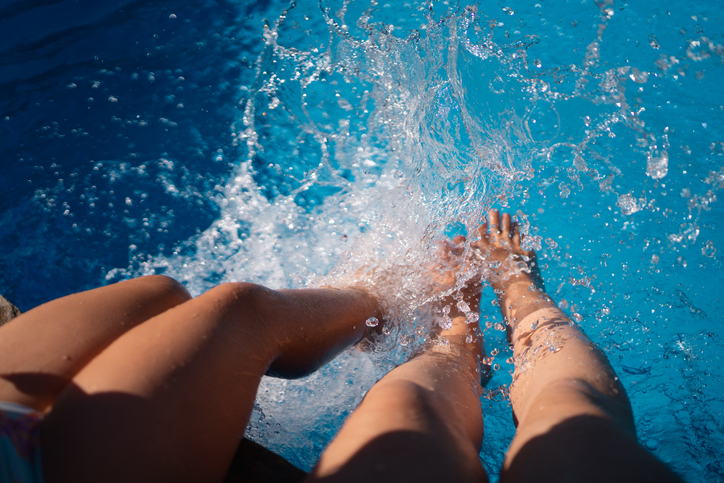 mother and daughter legs splashing in pool water