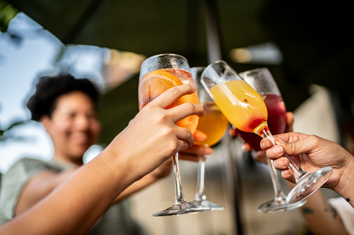 Close-up of friends toasting cocktails during happy hour at bar