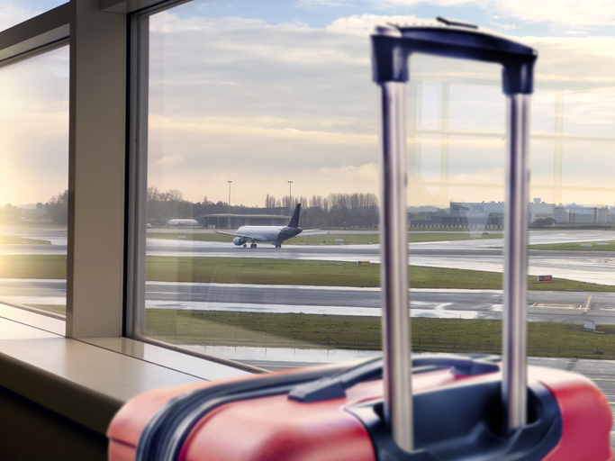 Airport departure area with red carry-on luggage