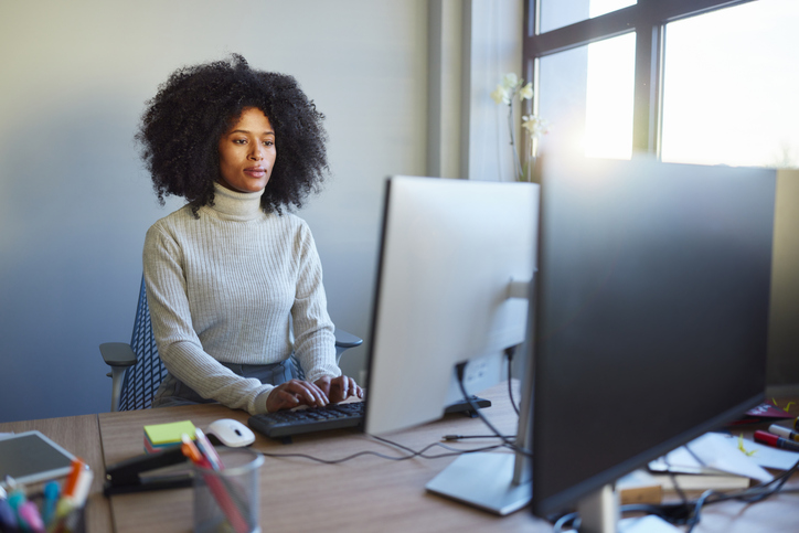 Black female programmer working on PC in the office.