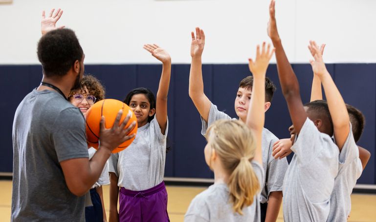 Elementary students in school gym playing basketball