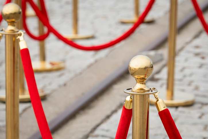 Golden stanchions with red velvet ropes. Concept of a VIP event, red carpet, premiere, or ceremony.