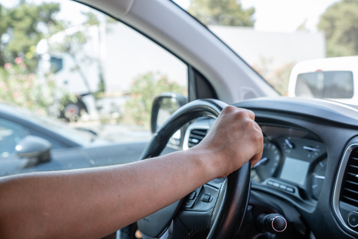 Driver Steers Vehicle Through Busy Parking Lot Under Bright Daylight in Urban Setting