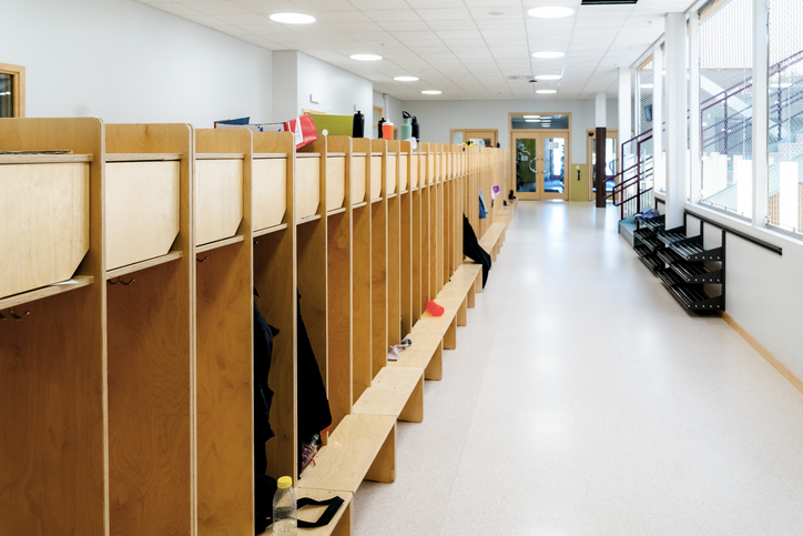 Empty corridor with wooden lockers in rows at elementary school