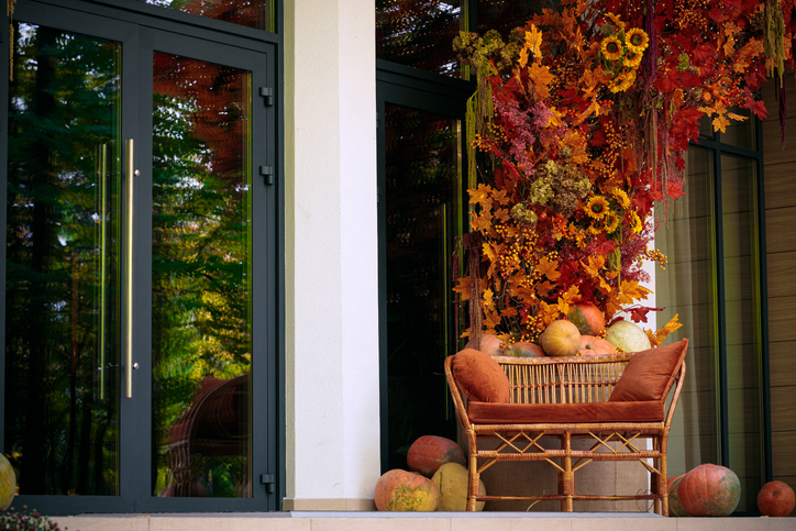 October season patio cottage villa external space cozy bench pillows and synthetic sun flowers orange colors and glass door entrance to house