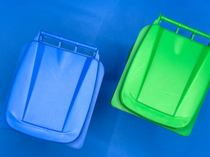 Directly above: Blue recycling bin lid and green recycling bin lid on blue background