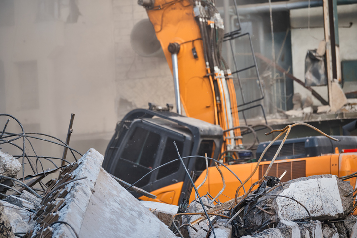 Destroying of old industrial building by excavator destroyer
