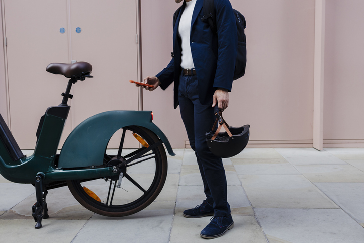 Business person with electric bike and smartphone outdoors