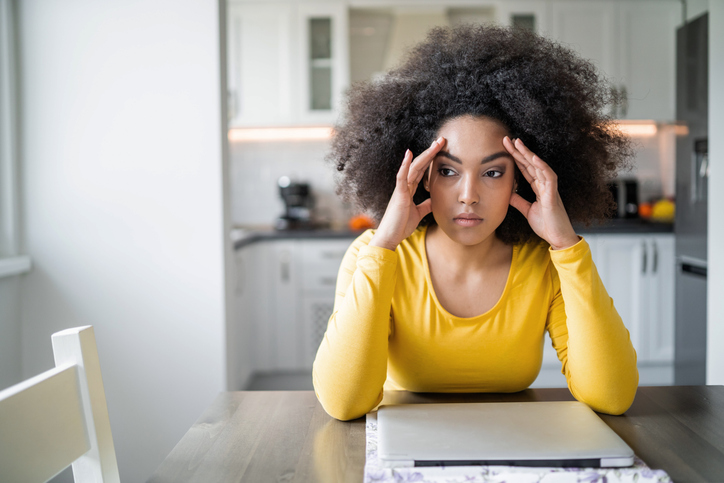 African american young woman dealing with financial problems and bills at home, sitting at the kitchen table
