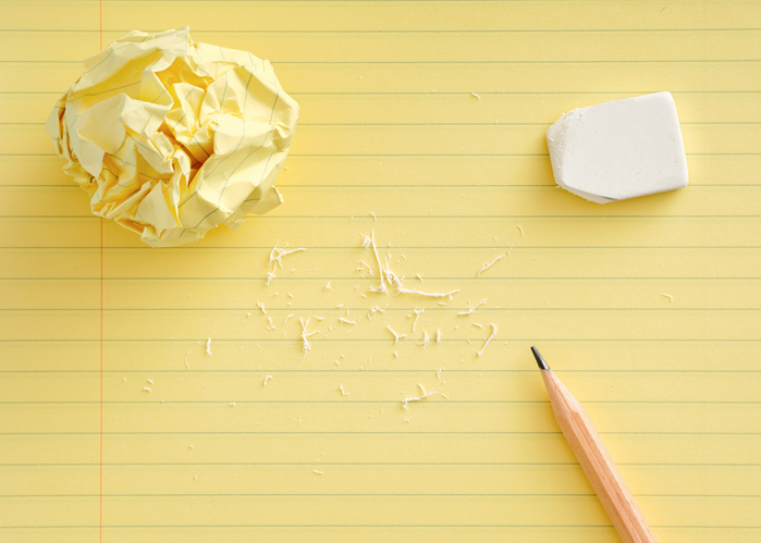Crumpled paper, eraser and pencil on yellow legal pad showing brainstorming and editing process