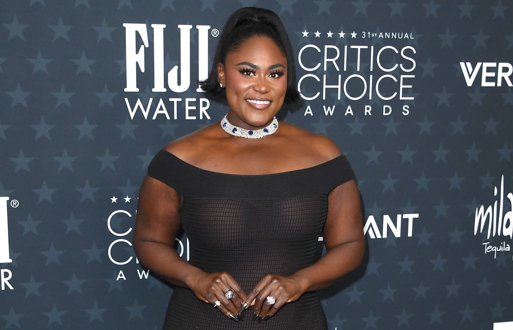 A woman in a black off-the-shoulder dress with a diamond choker necklace smiling at the 31st Annual Critics Choice Awards.