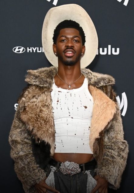 A man wearing a fur-trimmed coat and cowboy hat smiling at the camera.