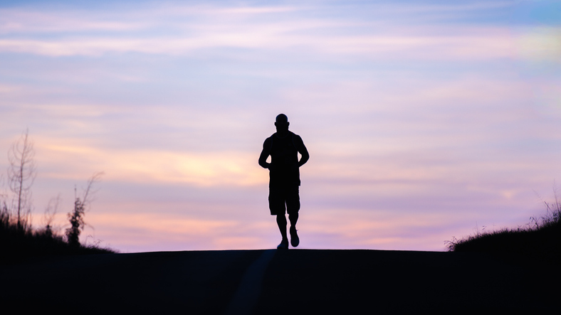 Silhouette Of A Runner Jogging At Sunrise On An Open Road For Fitness And Wellness