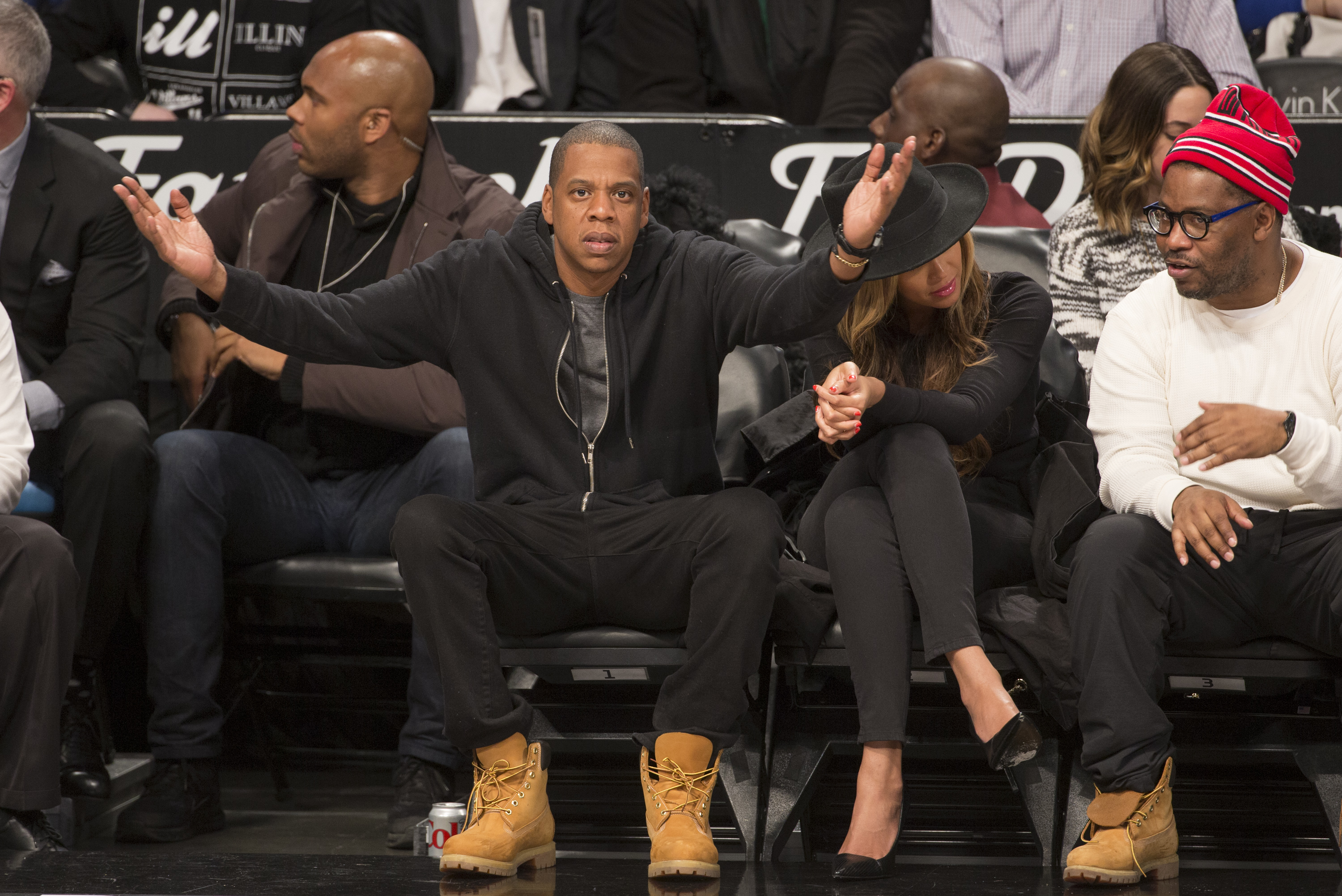 A group of people, including Jay-Z and Beyonce, sitting courtside at a basketball game at the Barclays Center in Brooklyn, New York.