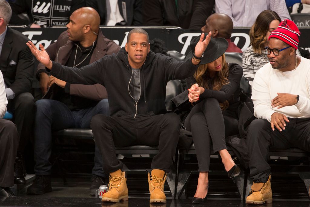 A group of people, including Jay-Z and Beyonce, sitting courtside at a basketball game at the Barclays Center in Brooklyn, New York.
