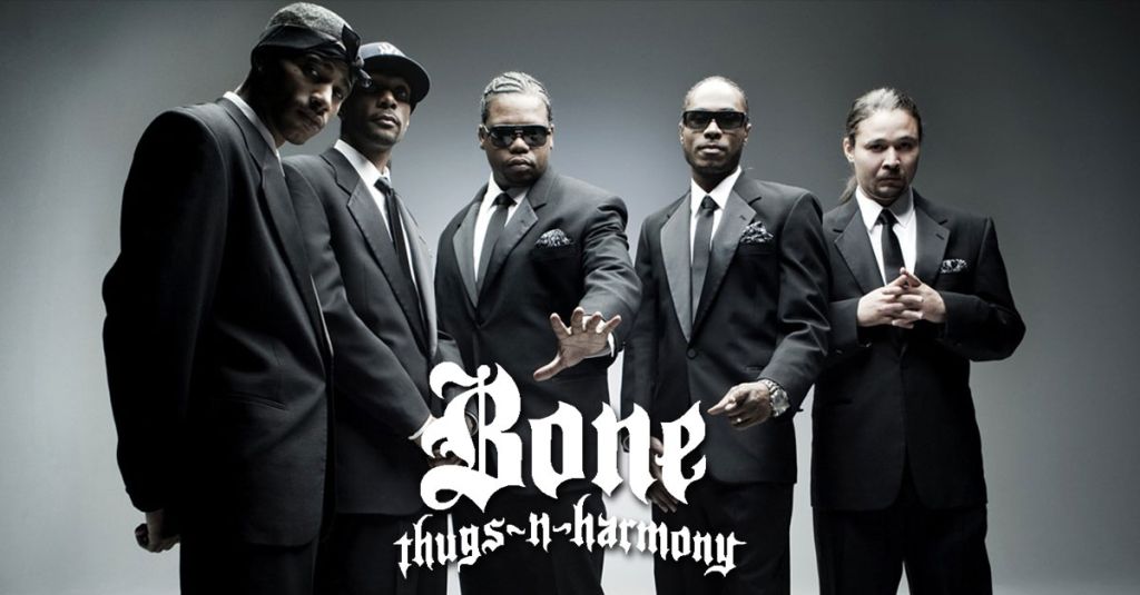 Five men in black suits and sunglasses standing together, with the text 