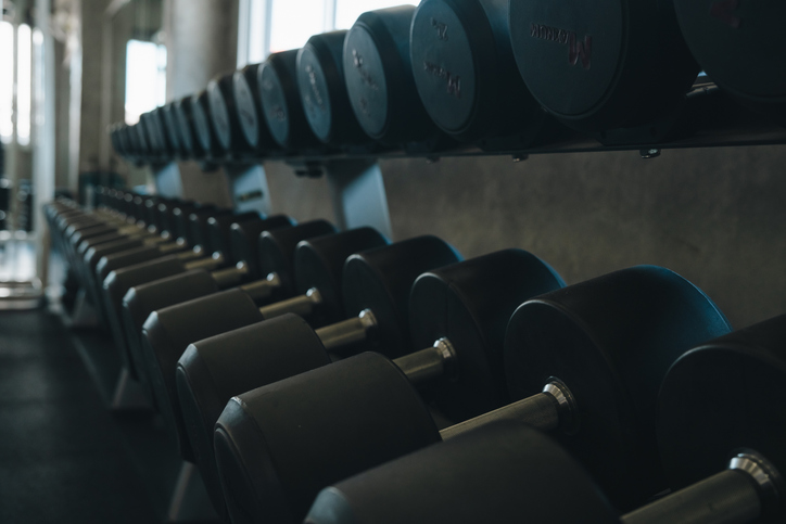 Dumbbell gym weight rack fitness exercise black metal equipment training arranged in row at indoor workout room with moody light and shallow focus