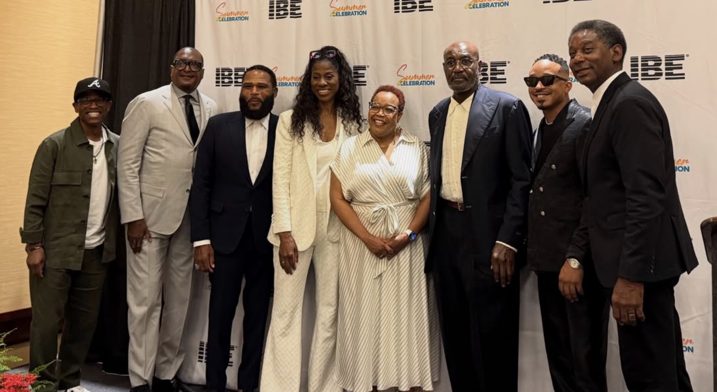 A group of well-dressed individuals posing for a photo at an event, with "CELEBRATION" and "IBE" branding visible in the background.