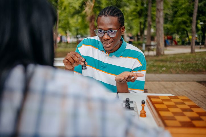 Friends playing chess in public park and having discussion